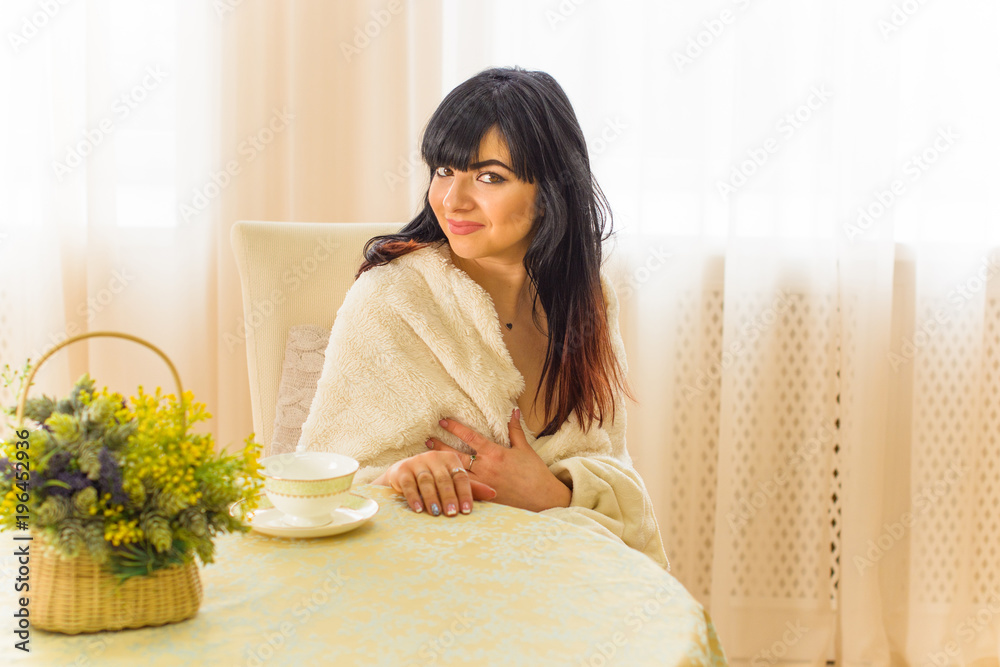 The concept of home comfort. A woman of Hispanic appearance at home in the apartment enjoys a good afternoon or evening 