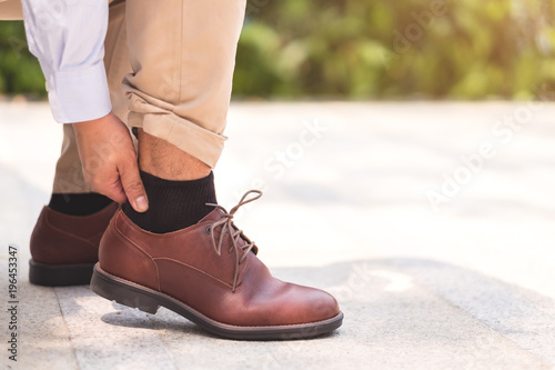 Businessman pain his feet and legs after walked a lot for his work