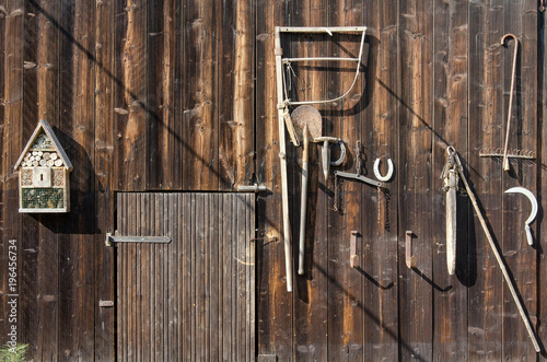 old rural tools hanging on a wooden barn door as decoration