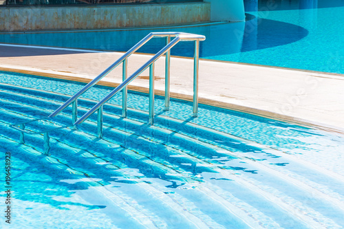 Blue swimming pool with stair at luxery hotel
