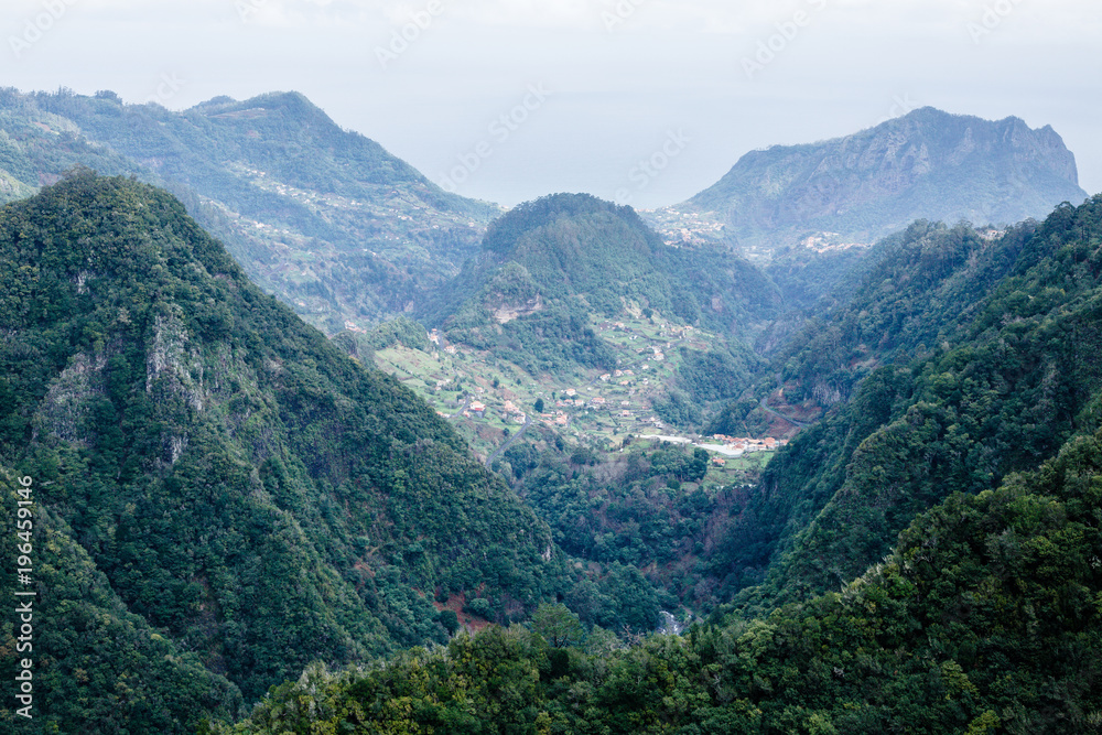 Small village in the valley surrounded by green mountains and ocean in Madeira, Portugal