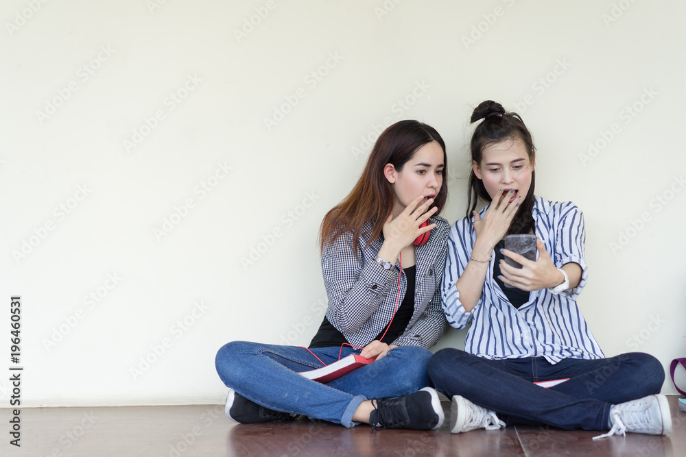 Teenagers women gossip girlfriend sharing secrets smiling sitting talking surprise in the ear and looking smartphone online news, copy space background Teenagers women gossip girlfriend sharing secrets smiling sitting talking surprise in the ear and looking smartphone online news, copy space background