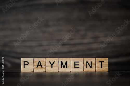 the word payment, consisting of light wooden square panels on a dark wooden background photo