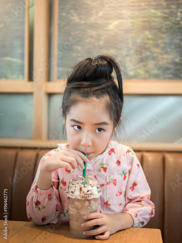 Beautiful asian girl drinking iced chocolate in the cafe, use  a straw