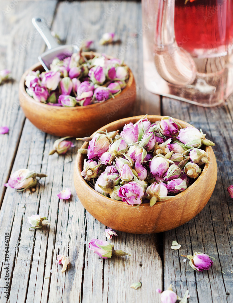 small dry buds of roses, tea, karkade, in wooden bowls, selective focus