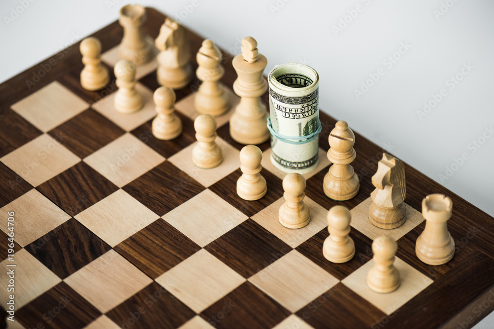 Chess board with cash and white chess pieces on white surface Chess board with cash and white chess pieces on white surface