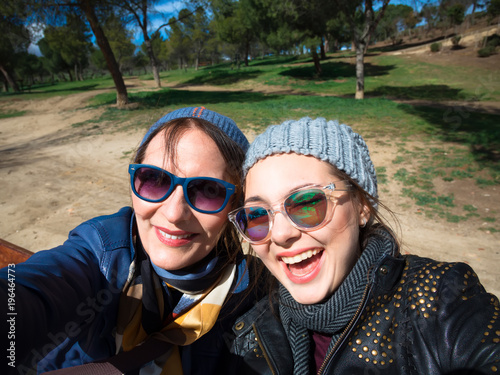 Schilderij op canvas Mother and adult daughter are doing selfie in park in summer going crazy and laughing