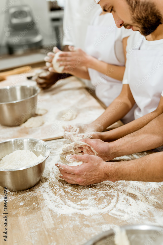 cropped shot of group of baking manufacture workers kneading dough together cropped shot of group of baking manufacture workers kneading dough together