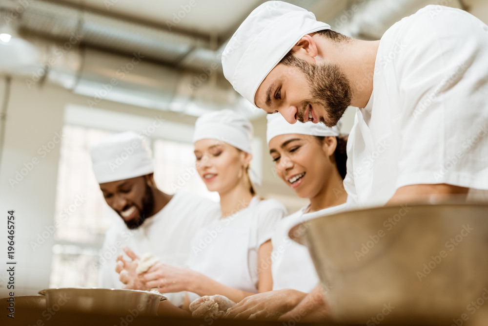 group of happy baking manufacture workers kneading dough together group of happy baking manufacture workers kneading dough together