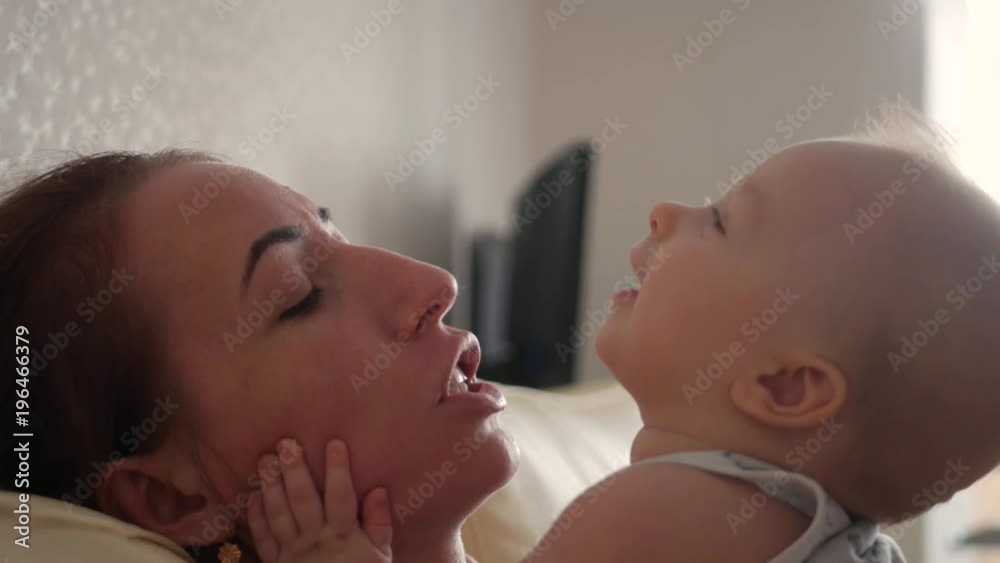 Young mother kissing sweet baby boy. Motherhood, family and parenthood concept - happy smiling young mother with little baby at home. Young mother kissing sweet baby boy. Motherhood, family and parenthood concept - happy smiling young mother with little baby at home.