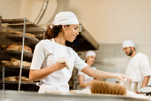 multiethnic team of bakers working together at baking manufacture