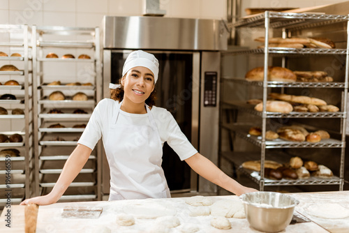 Obraz na plátně female baker standing at workplace on baking manufacture