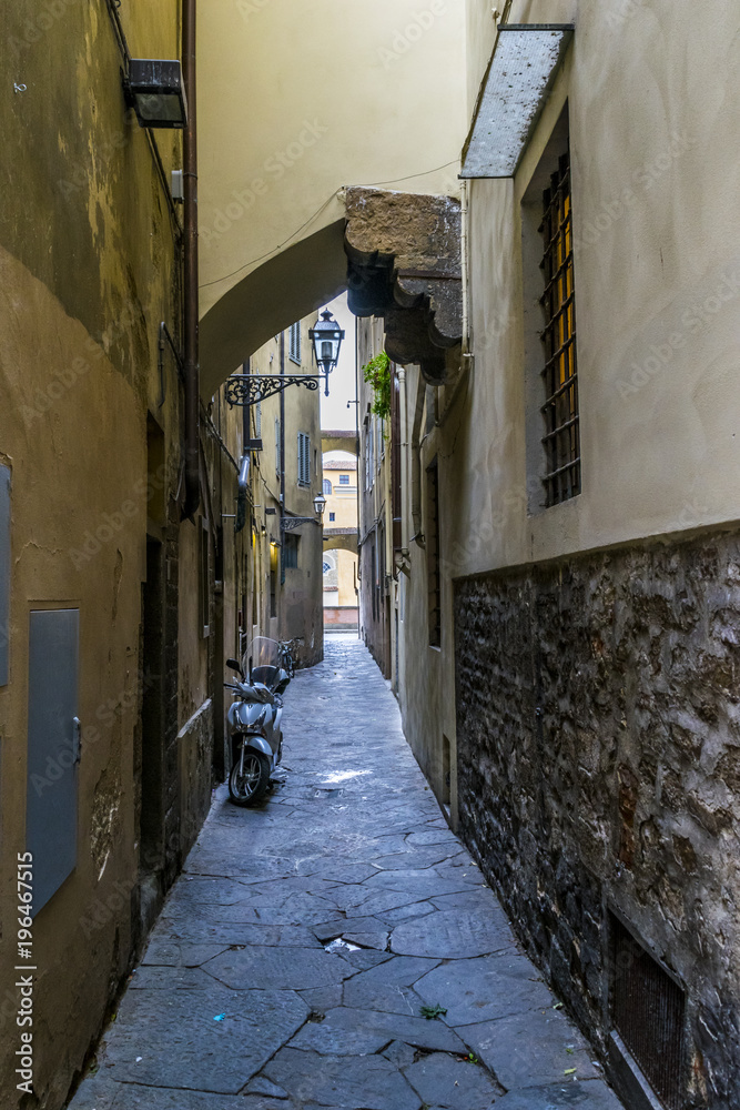 Narrow street in Florence, Italy.  Architectural details of old houses, parking motorcycle on the street.