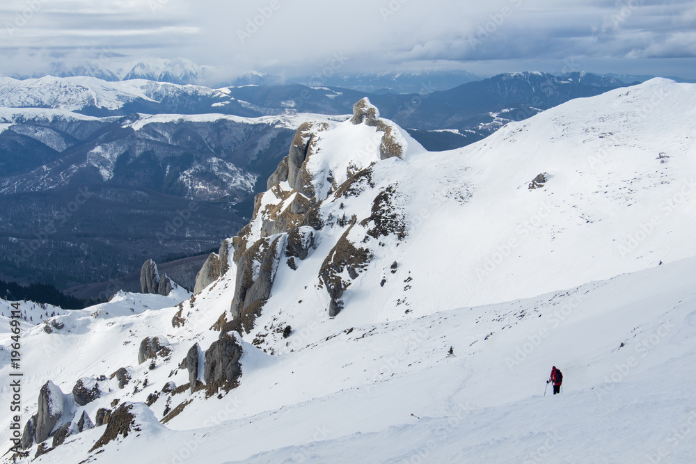 Lonely hiker descending snowy mountain slope Lonely hiker descending snowy mountain slope