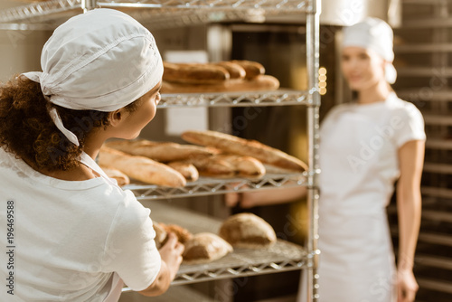 female bakers working together at baking manufacture and chatting