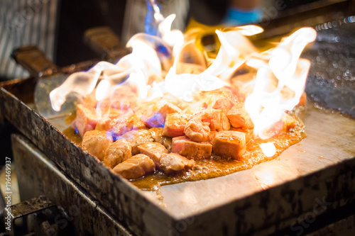 Cooking with grilled meat on a hot frying pan. Street food festival