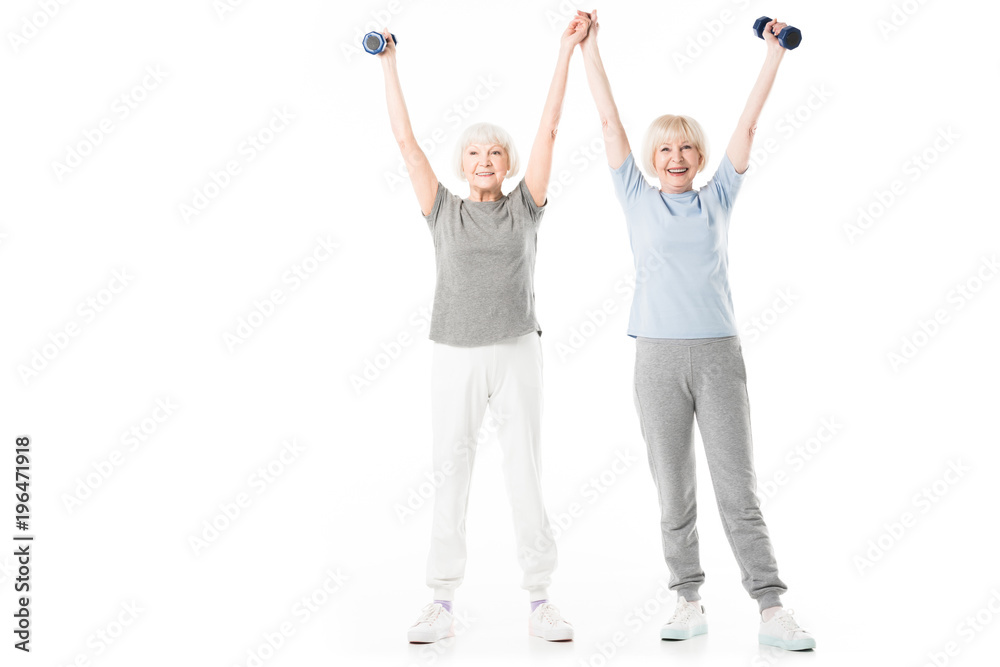 Senior sportswomen with arms up holding dumbbell isolated on white Senior sportswomen with arms up holding dumbbell isolated on white