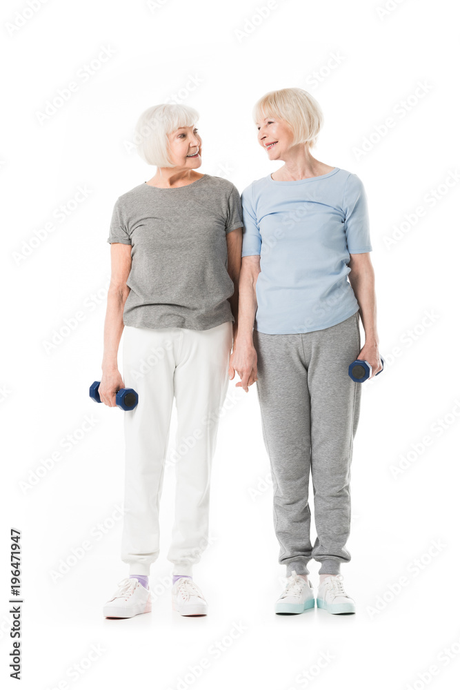 Senior sportswomen standing with dumbbell in hand isolated on white Senior sportswomen standing with dumbbell in hand isolated on white