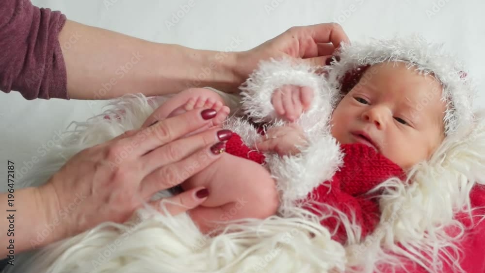 Tiny baby dressed as Santa Claus lying in the child's basket with his eyes open Tiny baby dressed as Santa Claus lying in the child's basket with his eyes open