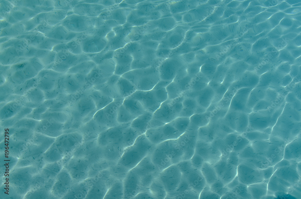clear transparent blue water and sun reflections on the white sand sea bottom of Porto Ceneviz Koyu Cirali, Antalya province, Turkey