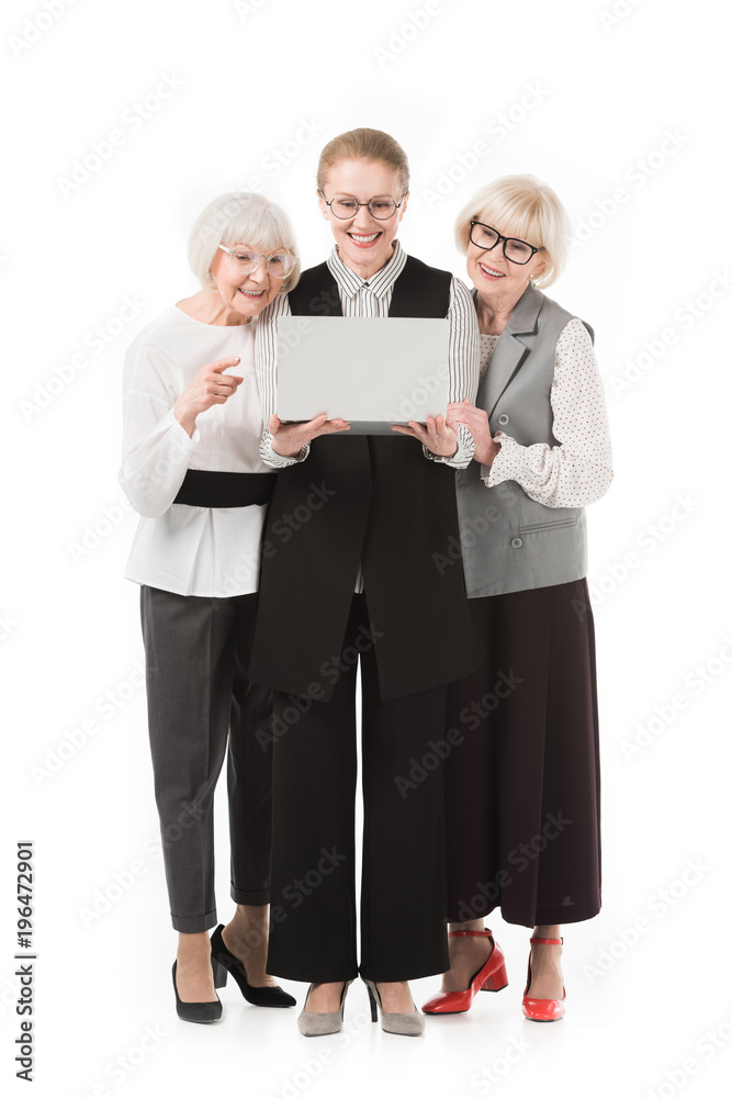 Stylish businesswomen in eyeglasses looking at laptop isolated on white