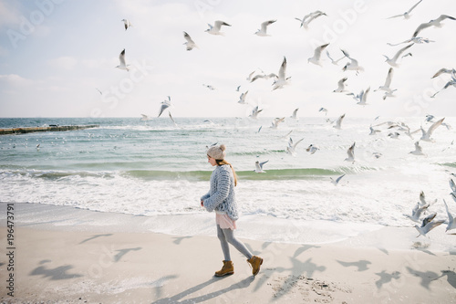 beautiful stylish girl on winter seashore with seagulls