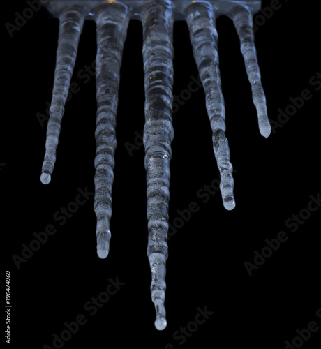 Icicles hanging down - isolated in a structured manner with black background.