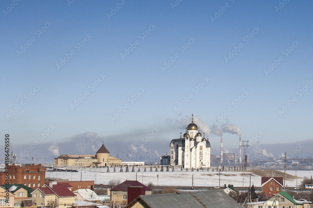 City landscape: Orthodox temple on the background of smoking pipes of metallurgical plant