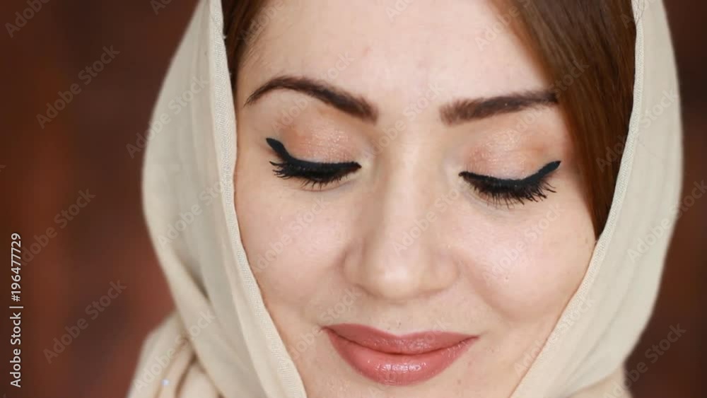 A beautiful Muslim woman in hijab smiles and looks at the camera. A mysterious sight. Close-up portrait A beautiful Muslim woman in hijab smiles and looks at the camera. A mysterious sight. Close-up portrait