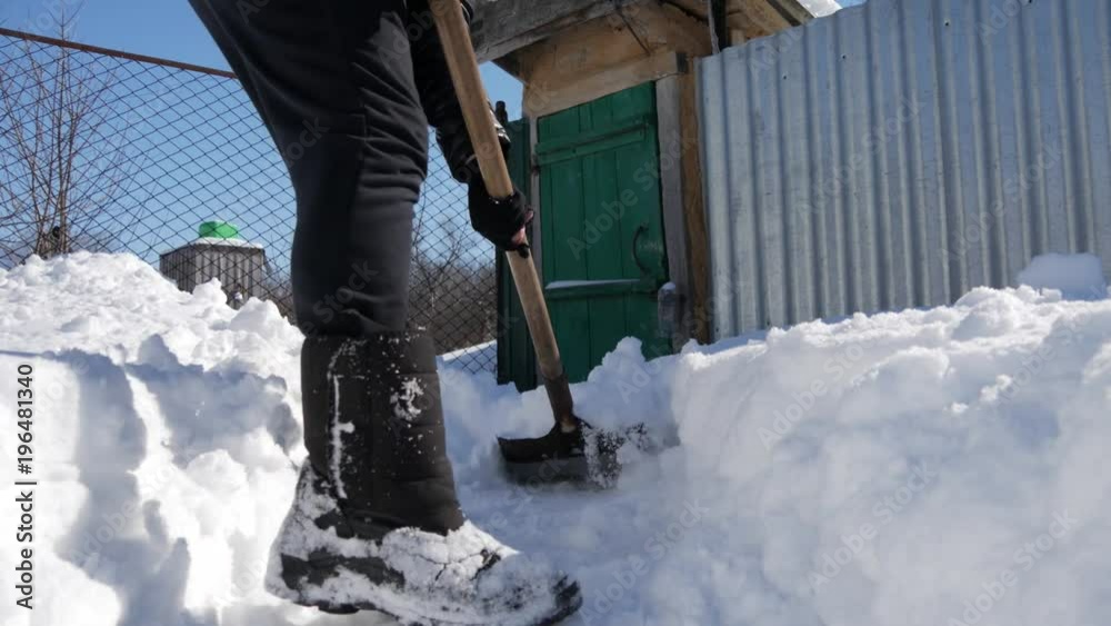 Young man shoveling and removing snow in front of her house in the suburb. Young man shoveling and removing snow in front of her house in the suburb.