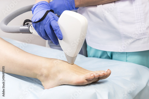 The process of laser depilation of female limbs in the beauty salon. 