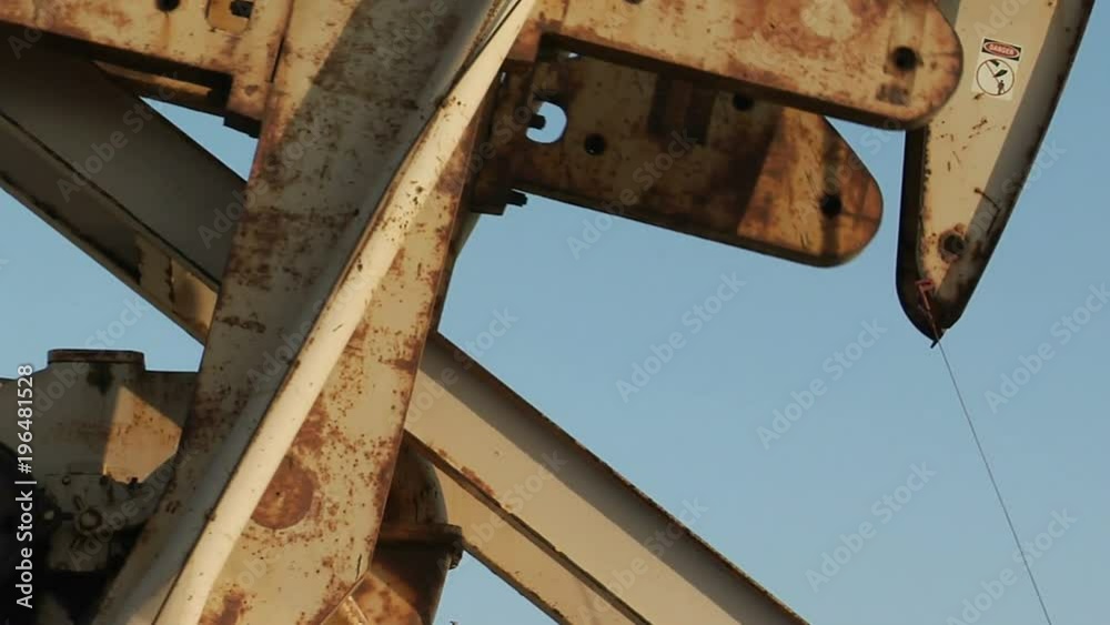 An oil derrick pumping oil passes before the sun. An oil derrick pumping oil passes before the sun.