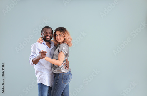 Cute interracial couple dancing against color background