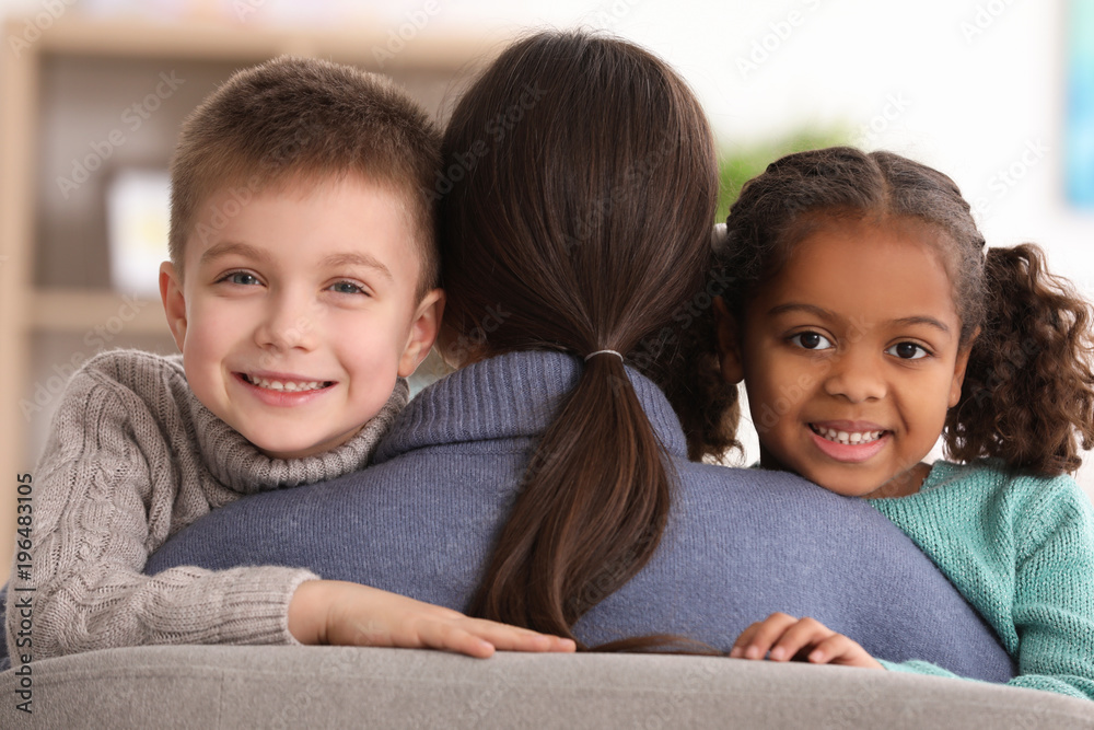 Woman hugging little kids indoors. Child adoption - obrazy, fototapety, plakaty 