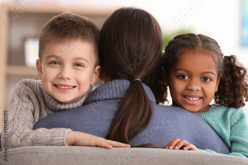 Woman hugging little kids indoors. Child adoption