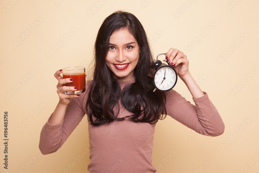 Young Asian woman with tomato juice and clock. Young Asian woman with tomato juice and clock.