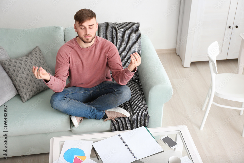 Young man relaxing in meditation posture at home Young man relaxing in meditation posture at home