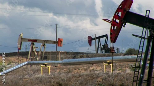 Pump jacks move up and down in an oil field.