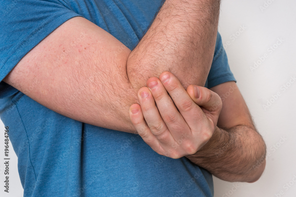 Man with elbow pain is holding his aching arm Man with elbow pain is holding his aching arm