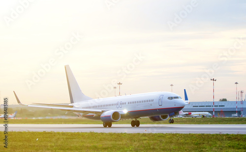 passenger plane fly up over take-off runway from airport at sunset