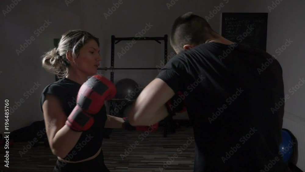 Young female student model taking self defense lessons from a professional male boxer in a gym sport studio in slow motion Young female student model taking self defense lessons from a professional male boxer in a gym sport studio in slow motion