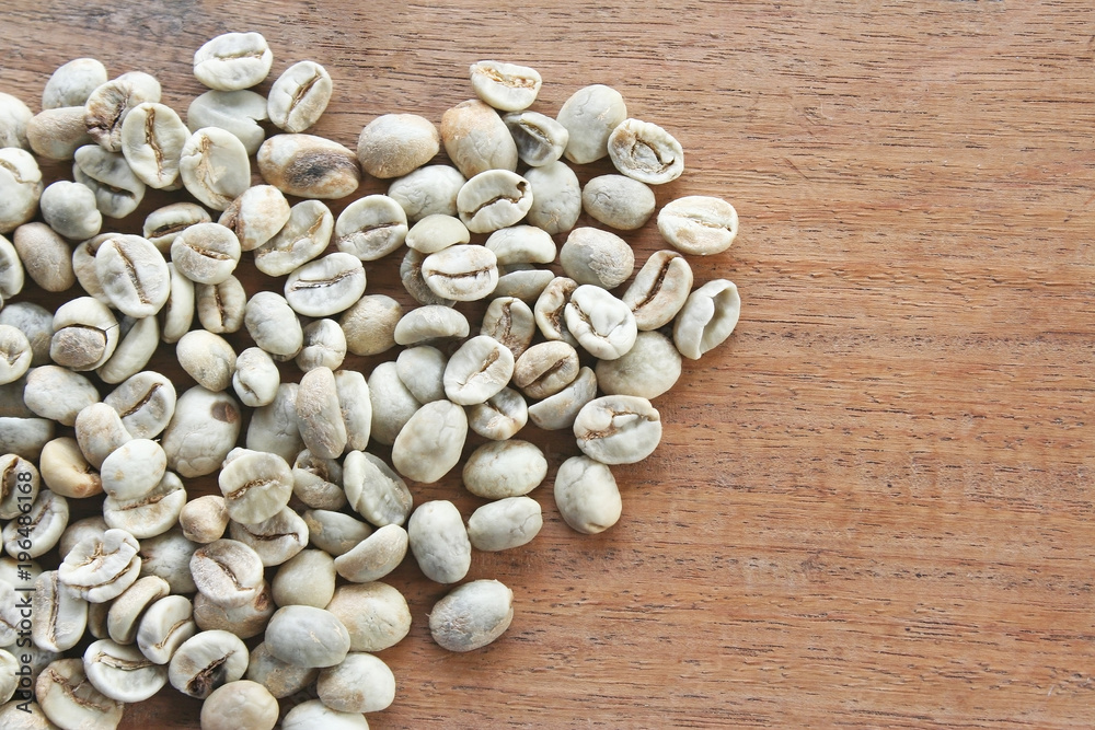 Many fresh raw coffee on wood table background