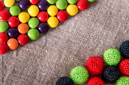 Chocolate candy in a colored glaze and fruit sweets on a gray textural fabric photo