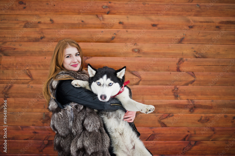 Red haired girl with husky dog against wooden wall. Red haired girl with husky dog against wooden wall.