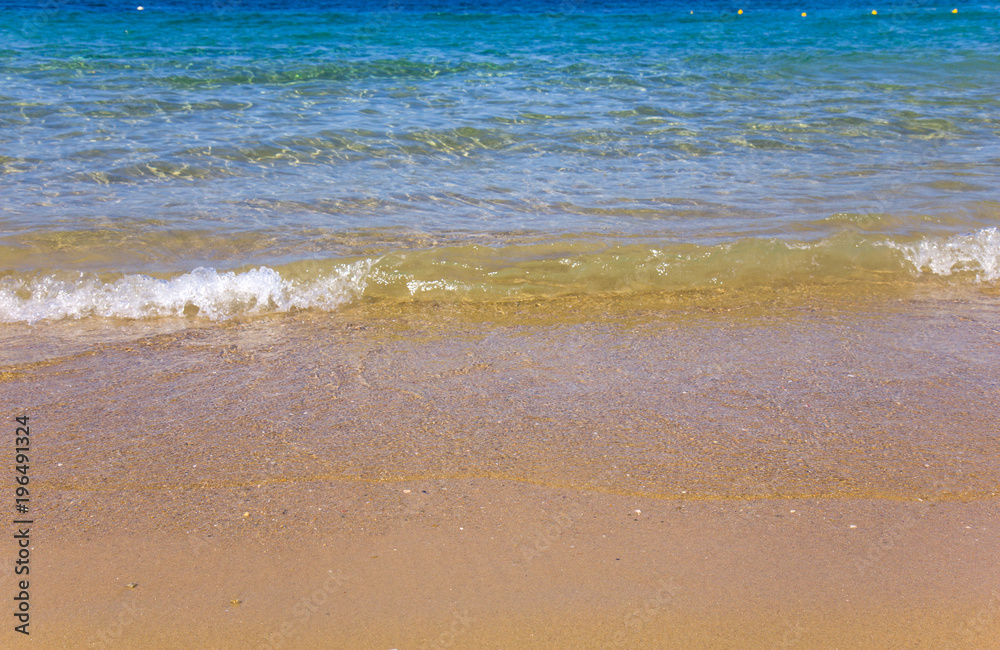 Seashore with blue water and orange sand and waves Seashore with blue water and orange sand and waves