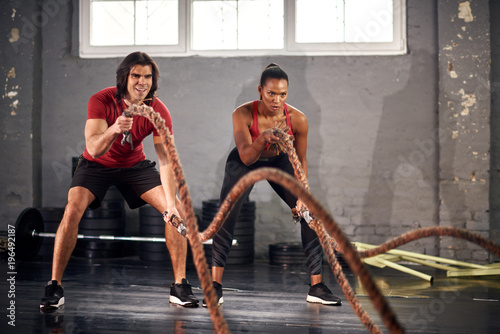 Man and woman working out with ropes in gym