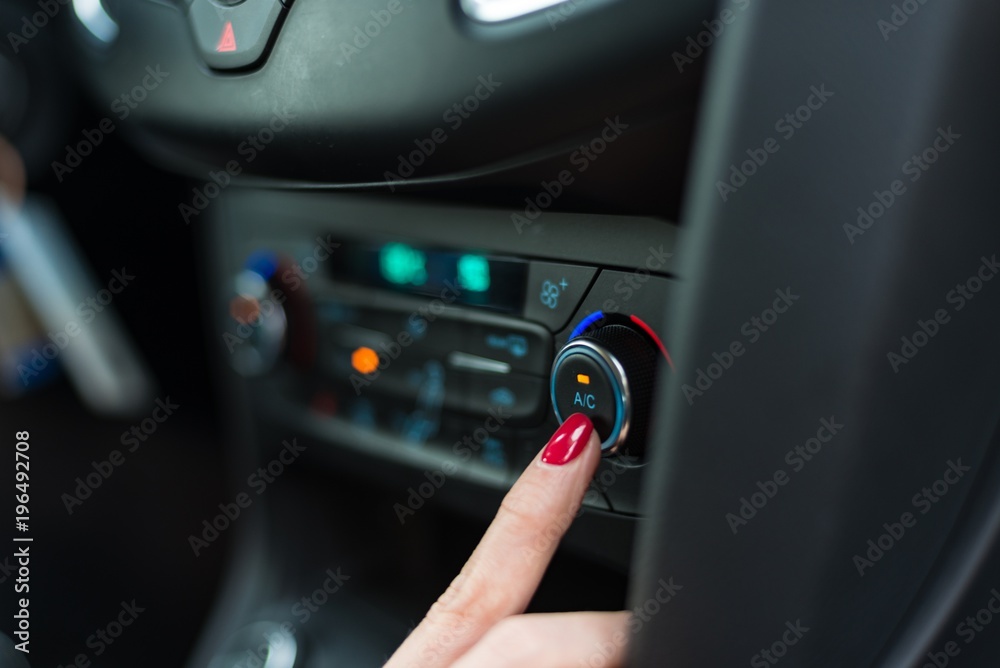 Woman turning on car air condition.