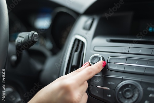 Woman adjusting volume on car radio
