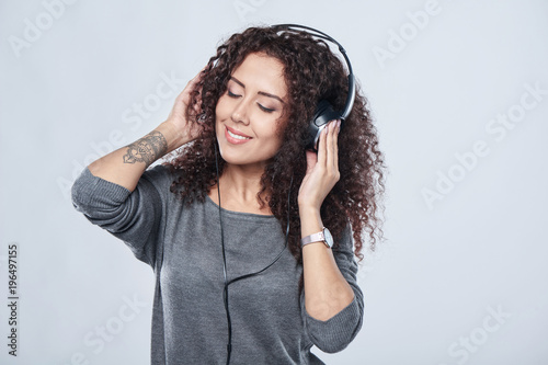 Woman listening enjoying music in headphones with closed eyes