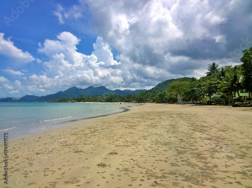 Fototapeta Naklejka Na Ścianę i Meble -  Blue sky and clouds over a tropical beach with green palm trees on Koh Chang island in Thailand